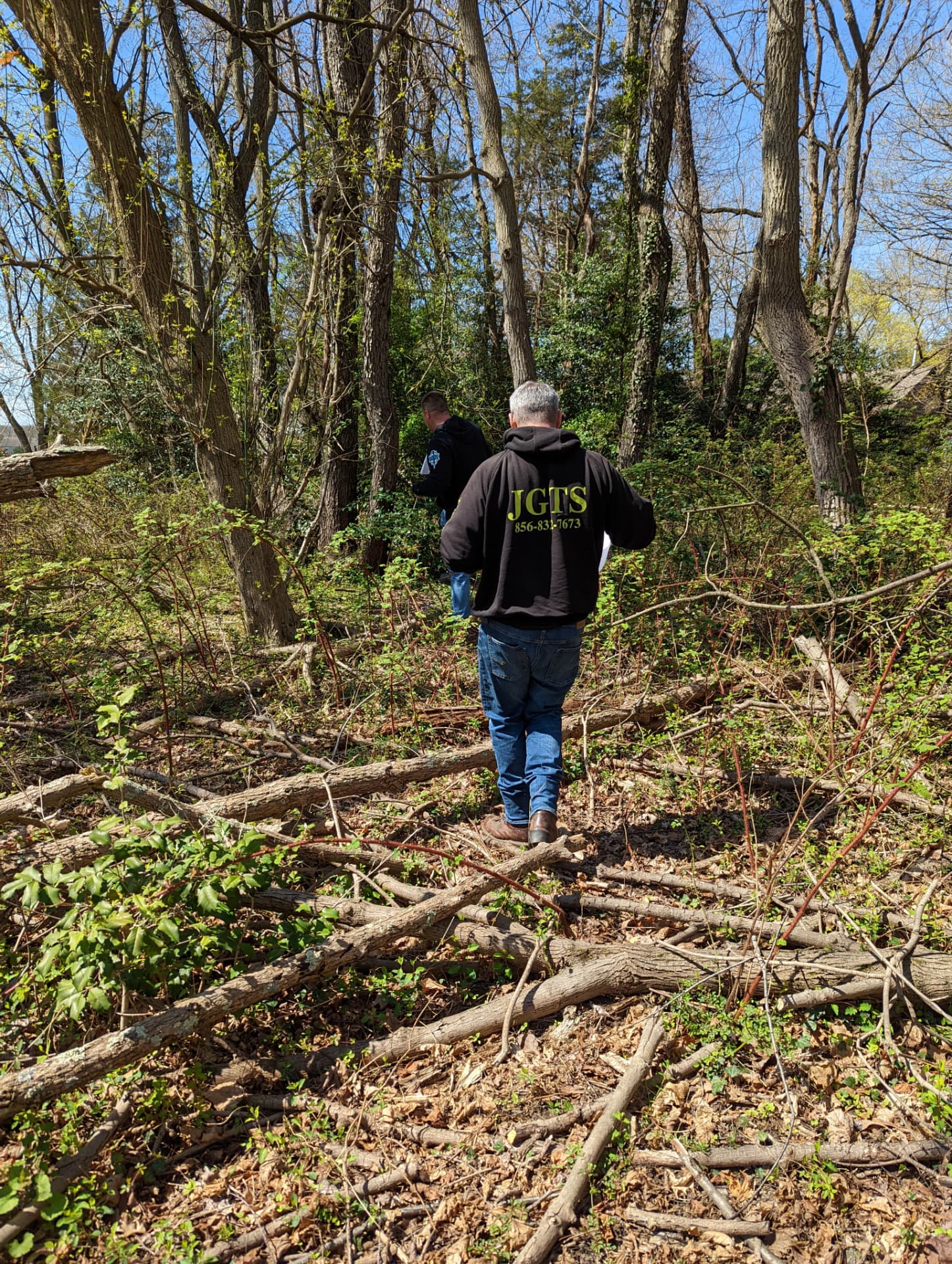Crew walking through overgrown woods with fallen limbs