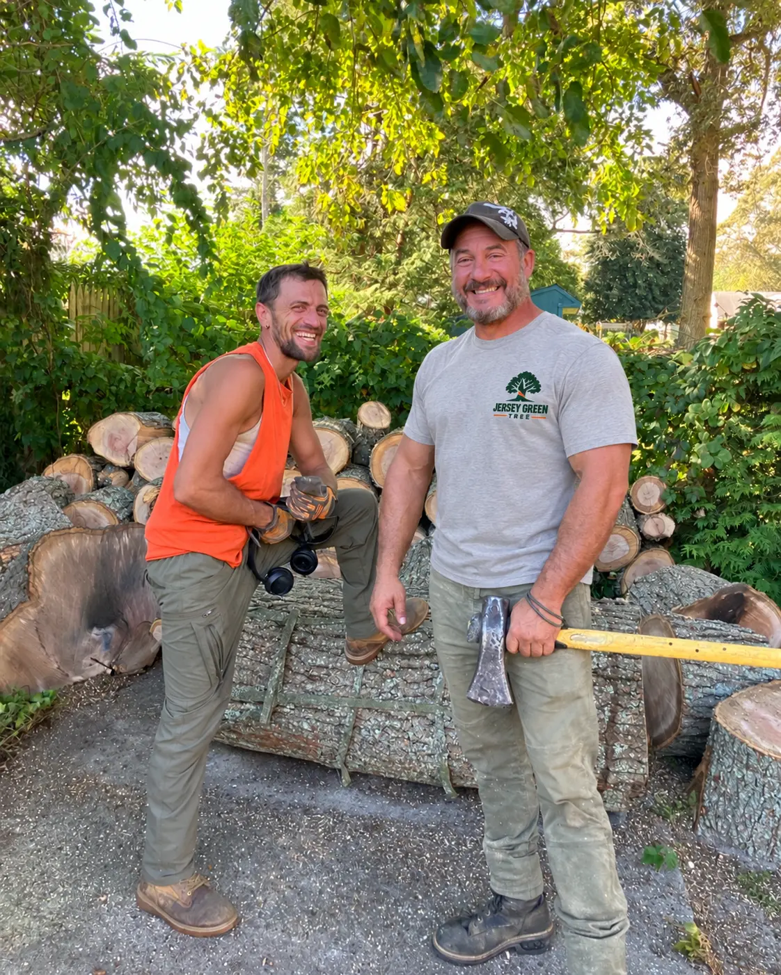 Tony, owner of Jersey Green Tree, with a crew member in front of a pile of cut logs